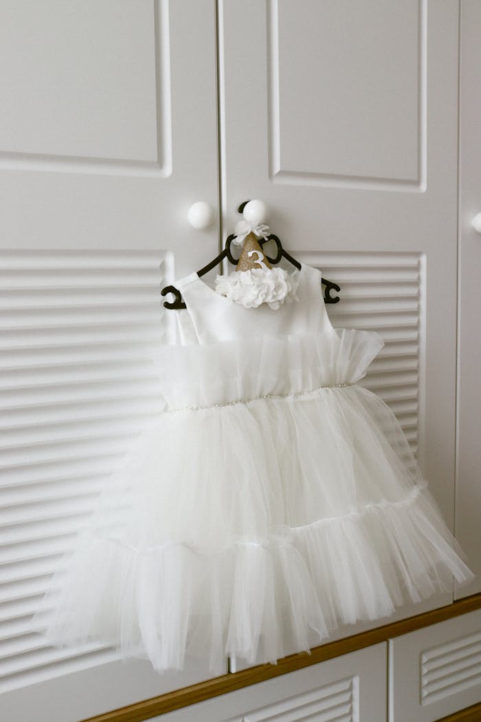 A white tulle dress hanging on a closet door, perfect for kids fashion.