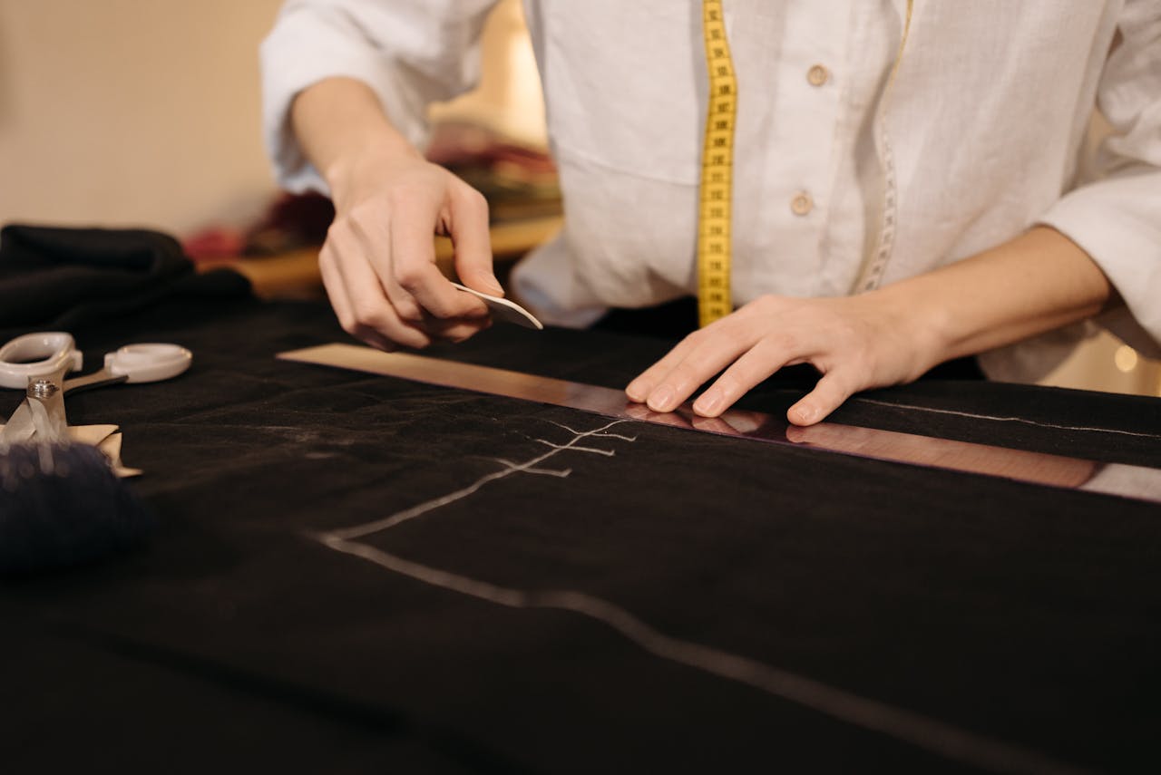 Close-up of hands marking fabric for sewing in a tailoring process.